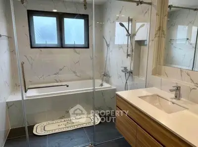 Modern bathroom with elegant marble tiles and sleek fixtures, featuring a spacious bathtub and stylish vanity.