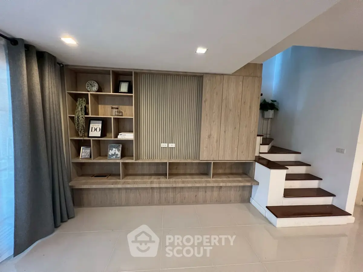 Modern living room with stylish wooden shelving and elegant staircase