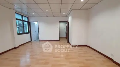 Spacious empty room with wooden flooring and large windows for natural light.