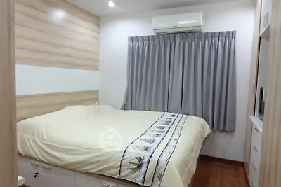 Cozy bedroom with modern design and air conditioning, featuring wooden accents and ample natural light.