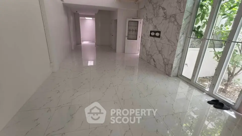 Spacious marble-floored interior with large windows and garden view, perfect for modern living.