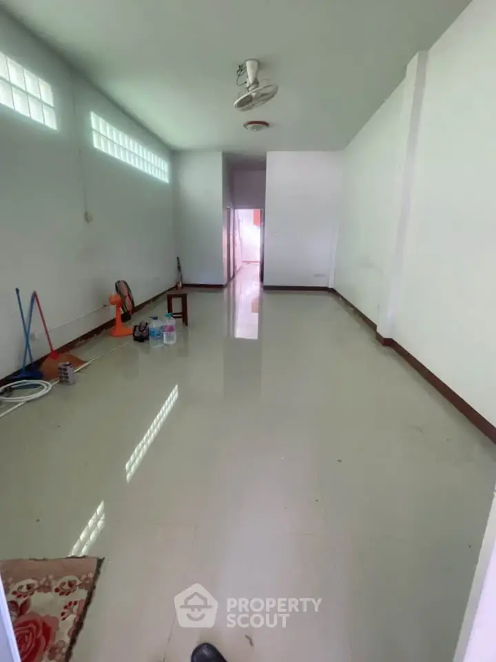 Spacious empty room with tiled flooring and natural light, ideal for customization.