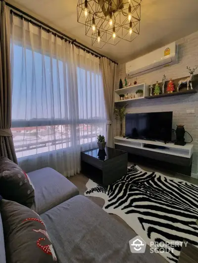 Cozy living room with stylish brick accent wall, modern chandelier, and expansive windows offering ample natural light and a snowy view, perfect for relaxing or entertaining guests.