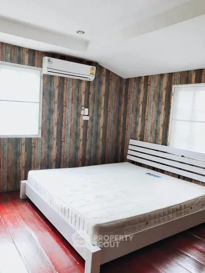 Cozy bedroom with wooden accent wall and natural light