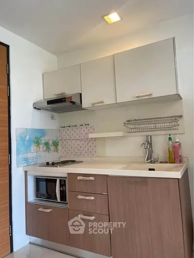 Modern compact kitchen with sleek cabinetry and built-in appliances in a stylish apartment.
