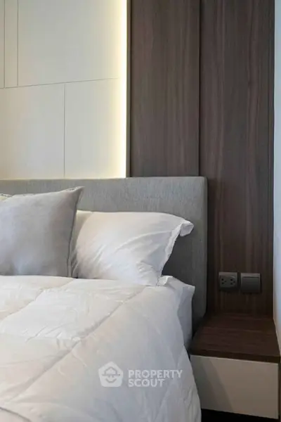 Modern bedroom with stylish headboard and cozy bedding in a contemporary apartment.