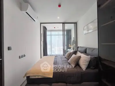 Modern bedroom with stylish decor and large window offering natural light.