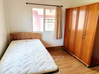 Cozy bedroom with wooden wardrobe and single bed, perfect for a minimalist lifestyle.