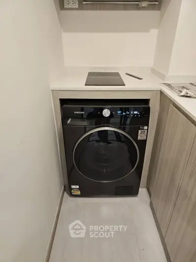 Modern kitchen with built-in Samsung washing machine and sleek countertop.