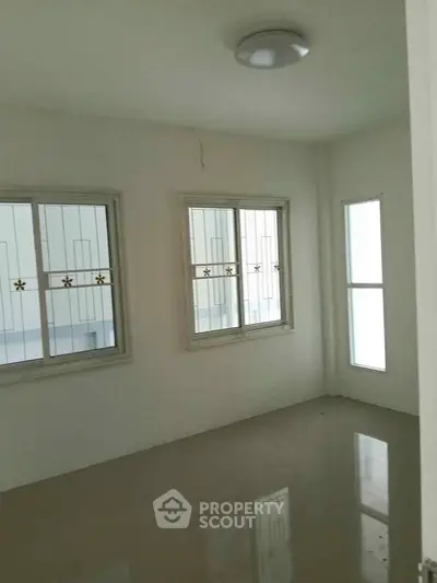 Spacious empty room with large windows and glossy floor, perfect for customization.