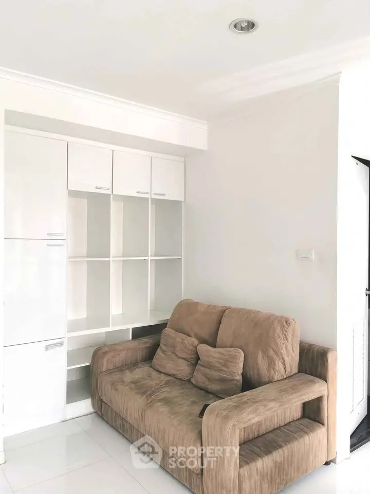 Cozy living room with modern beige sofa and white built-in shelves, perfect for relaxation.