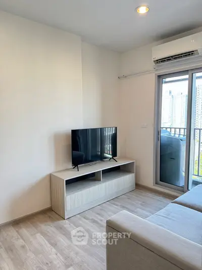 Modern living room with sleek TV setup and balcony view in urban apartment.