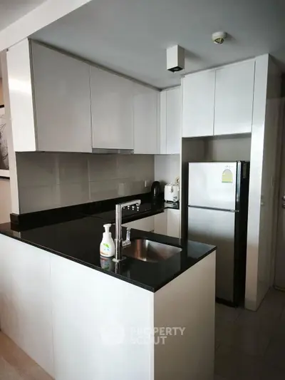 Modern kitchen with sleek white cabinets and black countertops in a stylish apartment.