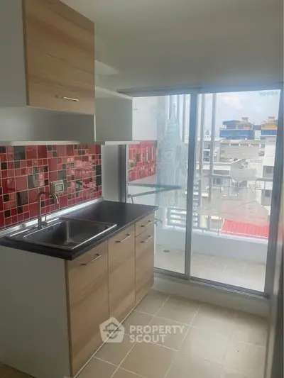 Modern kitchen with vibrant red backsplash and balcony view