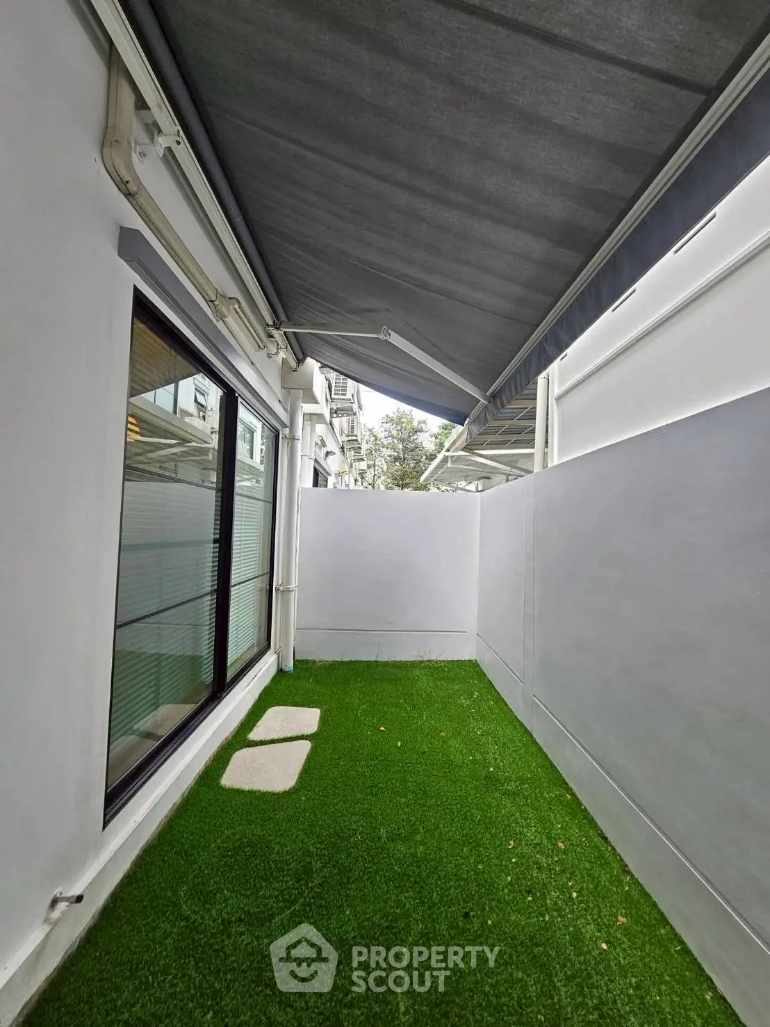 Charming outdoor space with artificial grass and awning, perfect for relaxation and privacy.