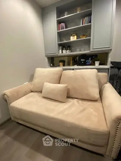 Cozy living room with plush beige sofa and built-in shelves, perfect for relaxation.