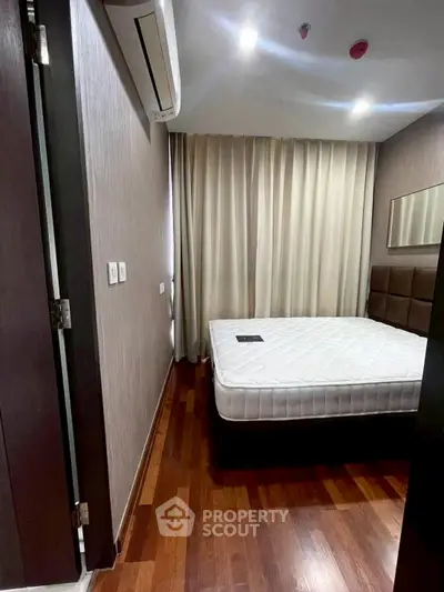 Cozy bedroom with wooden flooring and modern air conditioning unit.
