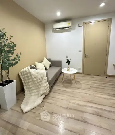 Cozy living room with modern decor and air conditioning, featuring a stylish sofa and elegant flooring.
