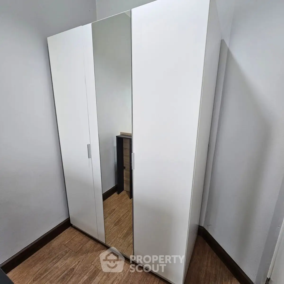 Modern white wardrobe with mirrored door in a cozy room corner