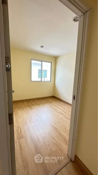 Bright empty room with wooden flooring and a window, perfect for customization.