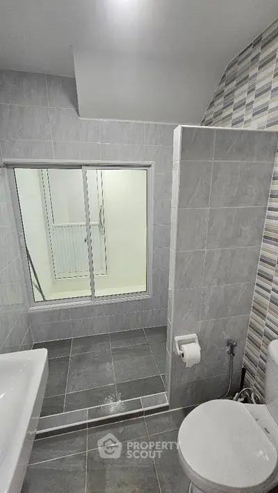 Modern bathroom with sleek gray tiles and glass shower enclosure