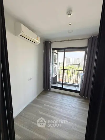 Modern bedroom with balcony view in urban apartment, featuring sleek air conditioning and elegant flooring.