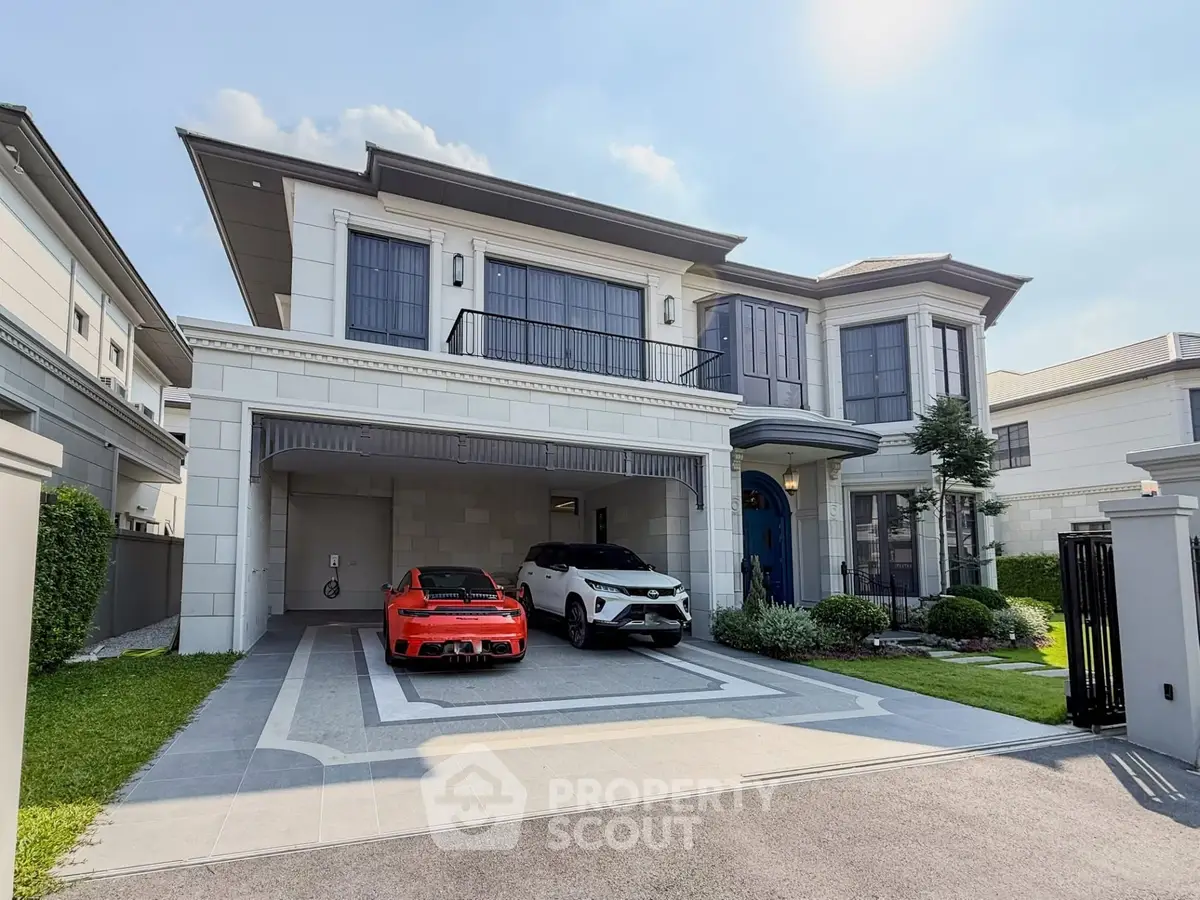 Luxurious modern house with spacious driveway and two cars parked, showcasing elegant architecture and manicured lawn.