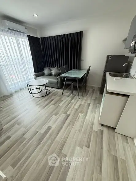 Modern living room with sleek furniture and open kitchen layout in a stylish apartment.