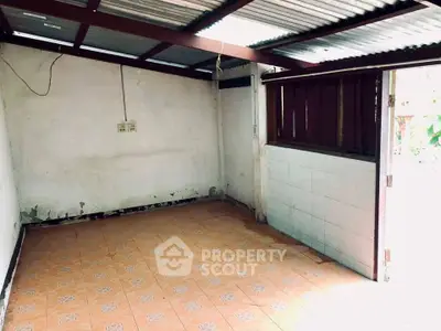 Spacious unfinished room with tiled floor and corrugated metal roof, ideal for renovation.