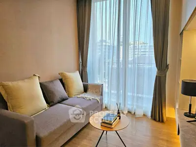 Cozy living room with modern sofa and natural light from large window.