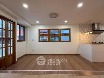 Spacious modern living room with wooden flooring and large windows in a stylish apartment.