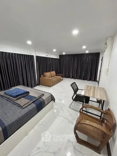 Spacious modern bedroom with elegant marble flooring and cozy seating area.