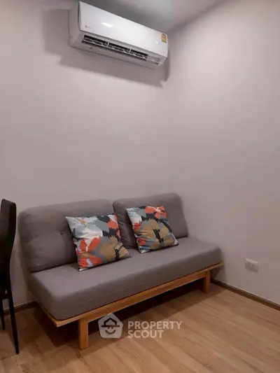 Cozy living room with modern sofa and air conditioning, perfect for relaxation.