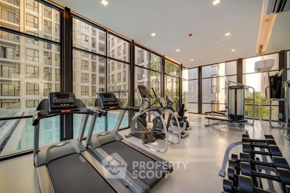 Modern gym with large windows and pool view in luxury apartment complex.