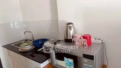 Compact kitchen with modern appliances including microwave and electric kettle, ideal for efficient cooking.