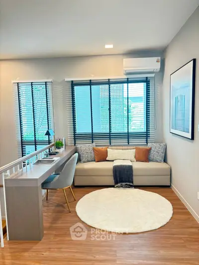 Modern living room with stylish decor, featuring a cozy sofa, sleek desk, and large windows with blinds.