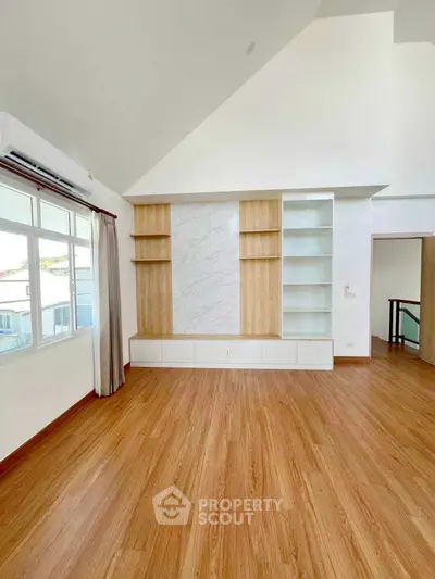 Spacious living room with wooden flooring and built-in shelves