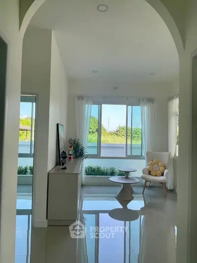 Bright living room with modern decor and large windows offering lush garden views.