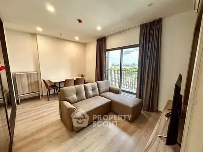 Modern living room with cozy sofa and dining area, featuring a large window with a scenic view.