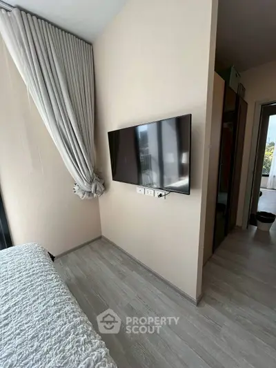 Modern bedroom with wall-mounted TV and elegant curtains