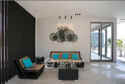 Modern living room with stylish decor and outdoor view, featuring sleek furniture and artistic wall design.