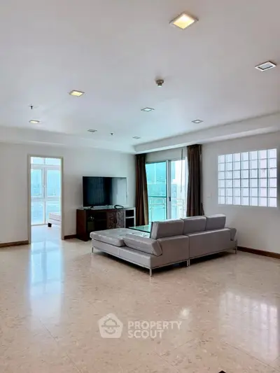 Spacious modern living room with sleek furniture and large windows offering natural light.