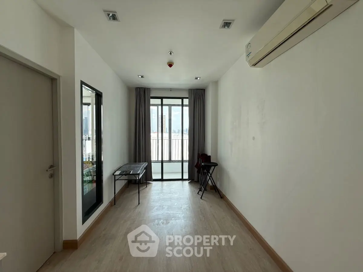 Spacious unfurnished room with large window and balcony access, featuring air conditioning and wooden flooring.