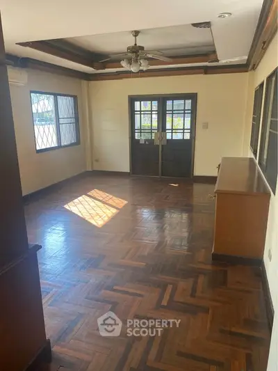 Spacious living room with wooden flooring and large windows for natural light.
