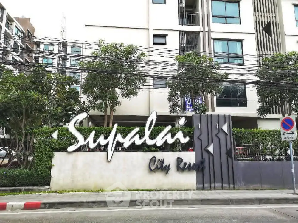 Modern city resort building exterior with lush greenery and stylish signage.