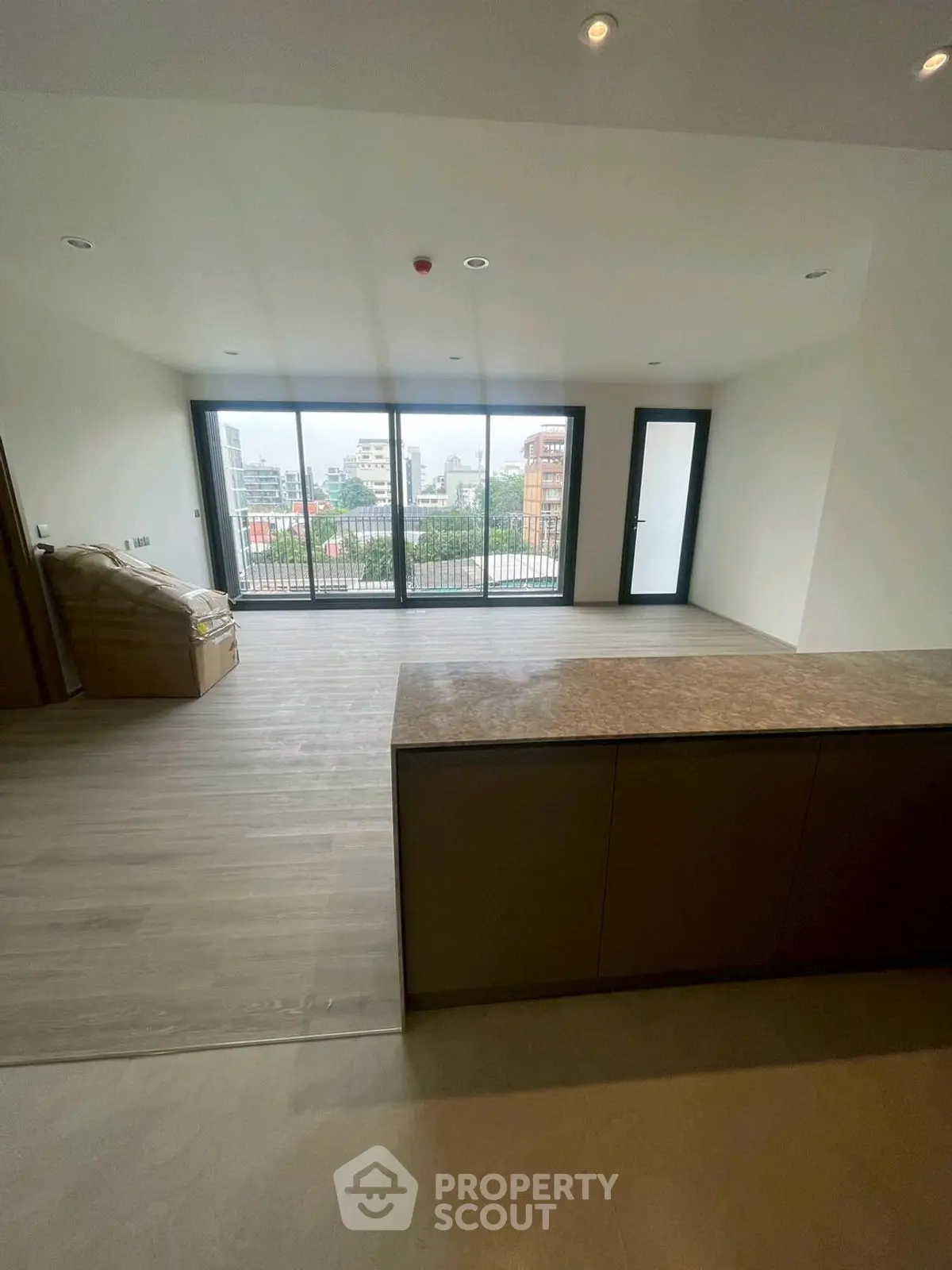 Spacious modern living room with large windows and balcony view in urban apartment.