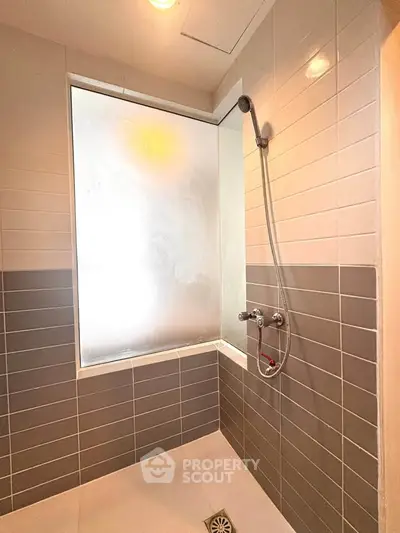 Modern bathroom with sleek shower design and frosted window for privacy.