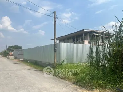 Explore this potential real estate investment with a fenced property under a clear blue sky.
