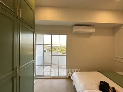 Cozy bedroom with green wardrobe and balcony view, featuring air conditioning.