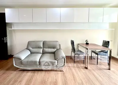 Modern living room with sleek sofa and dining area, featuring minimalist design and wooden flooring.